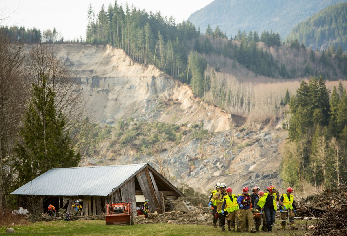 Rescue workers remove one of a number of bodies from the wreckage of homes destroyed by a mudslide near Oso, Wash., Monday, March 24, 2014. (AP Photo/seattlepi.com, Joshua Trujillo)   