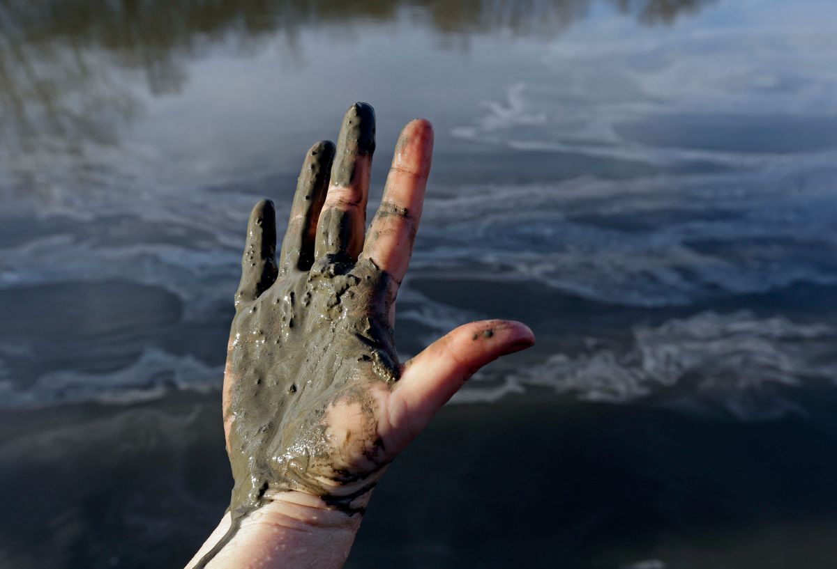 FILE - In this Feb. 5, 2014 file photo, Amy Adams, North Carolina campaign coordinator with Appalachian Voices, shows her hand covered with wet coal ash from the Dan River swirling in the background as state and federal environmental officials continued their investigations of a spill of coal ash into the river in Danville, Va.    (AP/Gerry Broome)