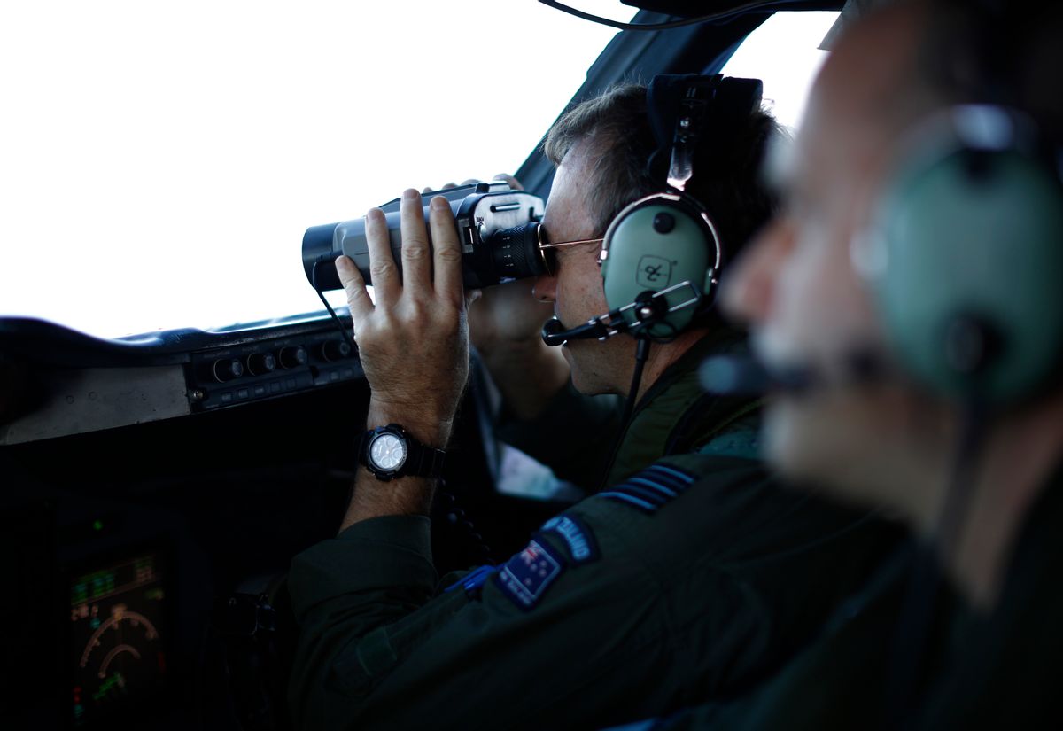 Wing Commander Rob Shearer looks through binoculars on the flight deck of a Royal New Zealand Air Force P-3K2 Orion aircraft searching for missing Malaysian Airlines flight 370 over the southern Indian Ocean, March 29, 2014.  (AP Photo/Jason Reed, Pool)  