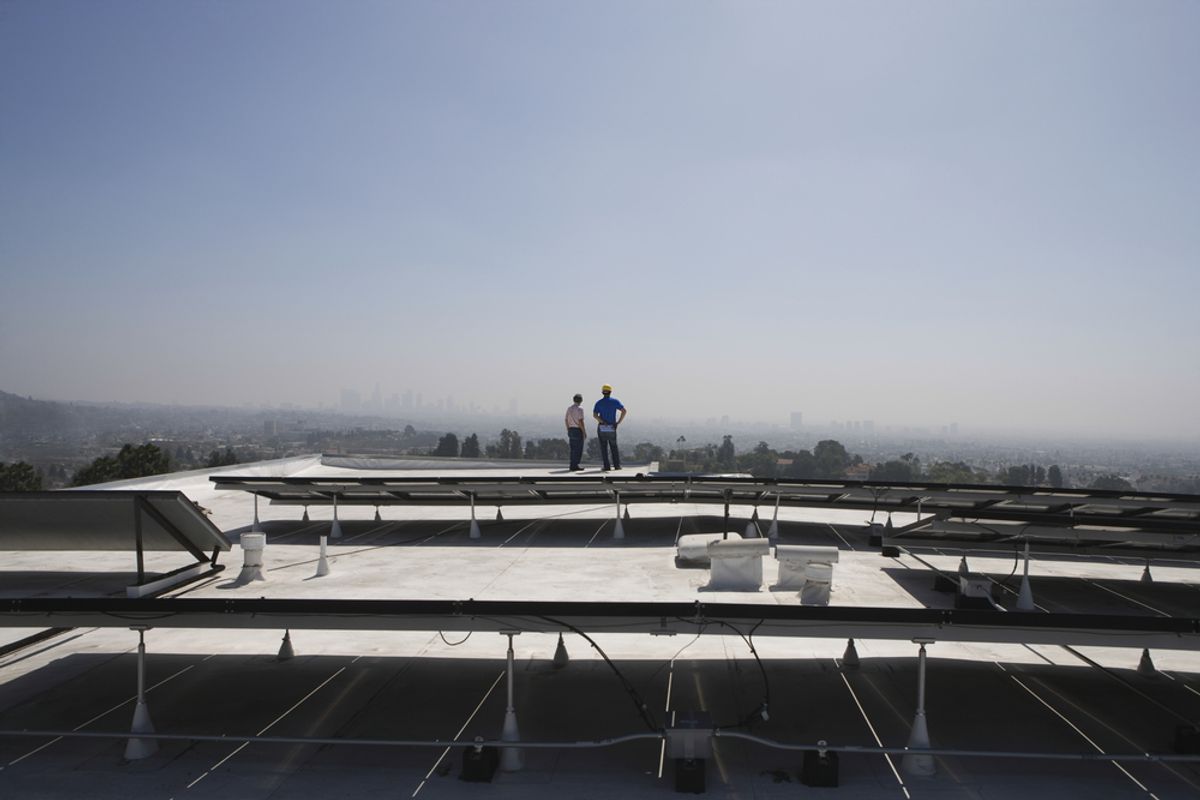 Maintenance workers near solar panels on a rooftop in Los Angeles (bikeriderlondon/Shutterstock)