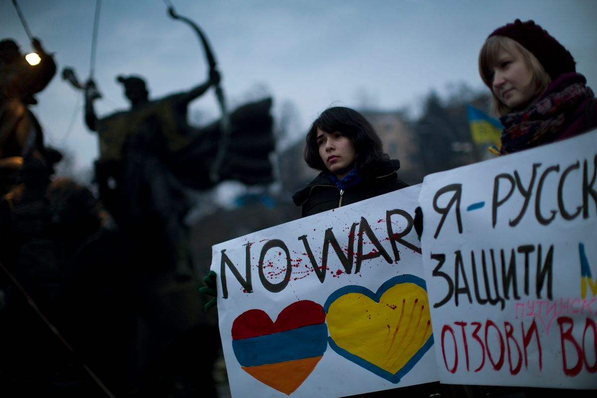Ukrainian Maria, 23, right, and Vanui, 22, hold posters against Russia's military intervention in Crimea, in Kiev, Ukraine, Sunday, March 2, 2014. Russia's parliament approved a motion to use the country's military in Ukraine after a request from President Vladimir Putin as protests in Russian-speaking cities turned violent Saturday, sparking fears of a wide-scale invasion. The poster in the right side reads in Ukrainian: "I am from Russia, please protect me and remove the weapons and soldiers from Ukraine." (AP Photo/Emilio Morenatti)  (AP)