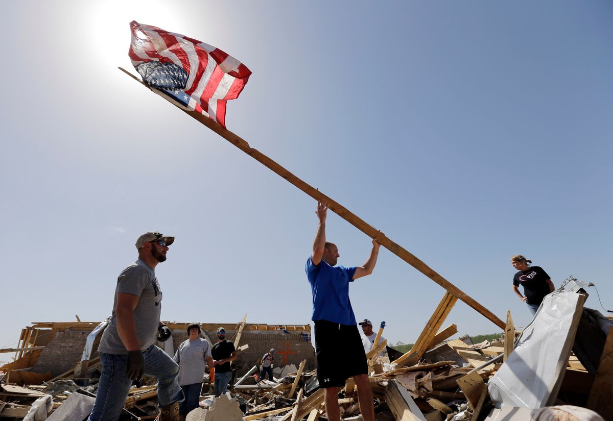 Justin Shaw, left, helps Nick Conway erect a flag pole at his home that was destroyed by a tornado, Monday, April 28, 2014, in Vilonia, Ark. (AP Photo/Eric Gay) (AP)