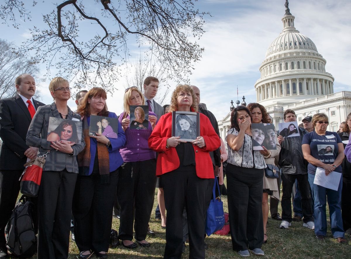 Calling themselves GM Recall Survivors, families of victims of a General Motors safety defect in small cars hold photos of their loved ones (AP)