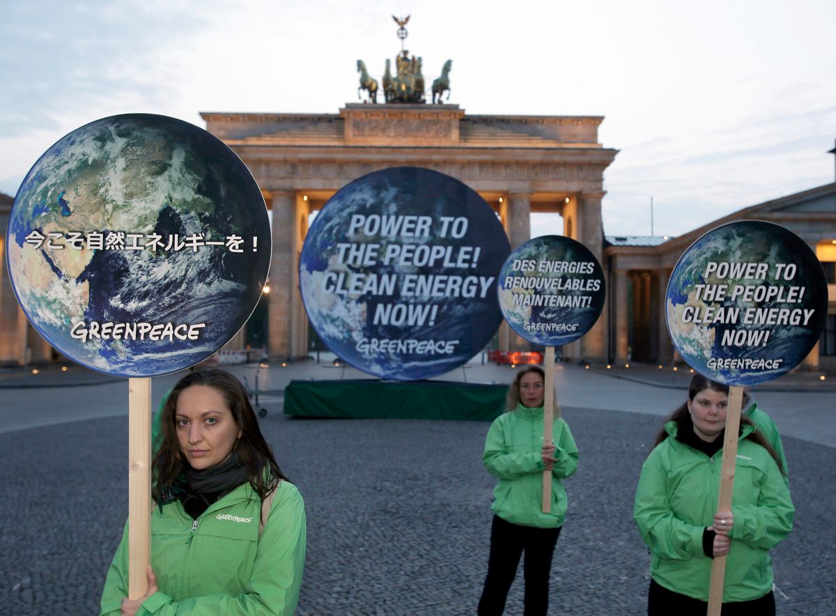 Activists of the international environmentalist organization Greenpeace pose with posters in front of the Brandenburg Gate in Berlin, Germany, Sunday, April 13, 2014  to support clean energy. After a one week meeting of the Intergovernmental Panel on Climate Change in Berlin the final document which is released on Sunday is expected to say that a global shift to renewable energy from fossil fuels like oil and coal are required to avoid potentially devastating sea level rise, flooding, droughts and other impacts of warming. (AP Photo/Michael Sohn) (Michael Sohn)