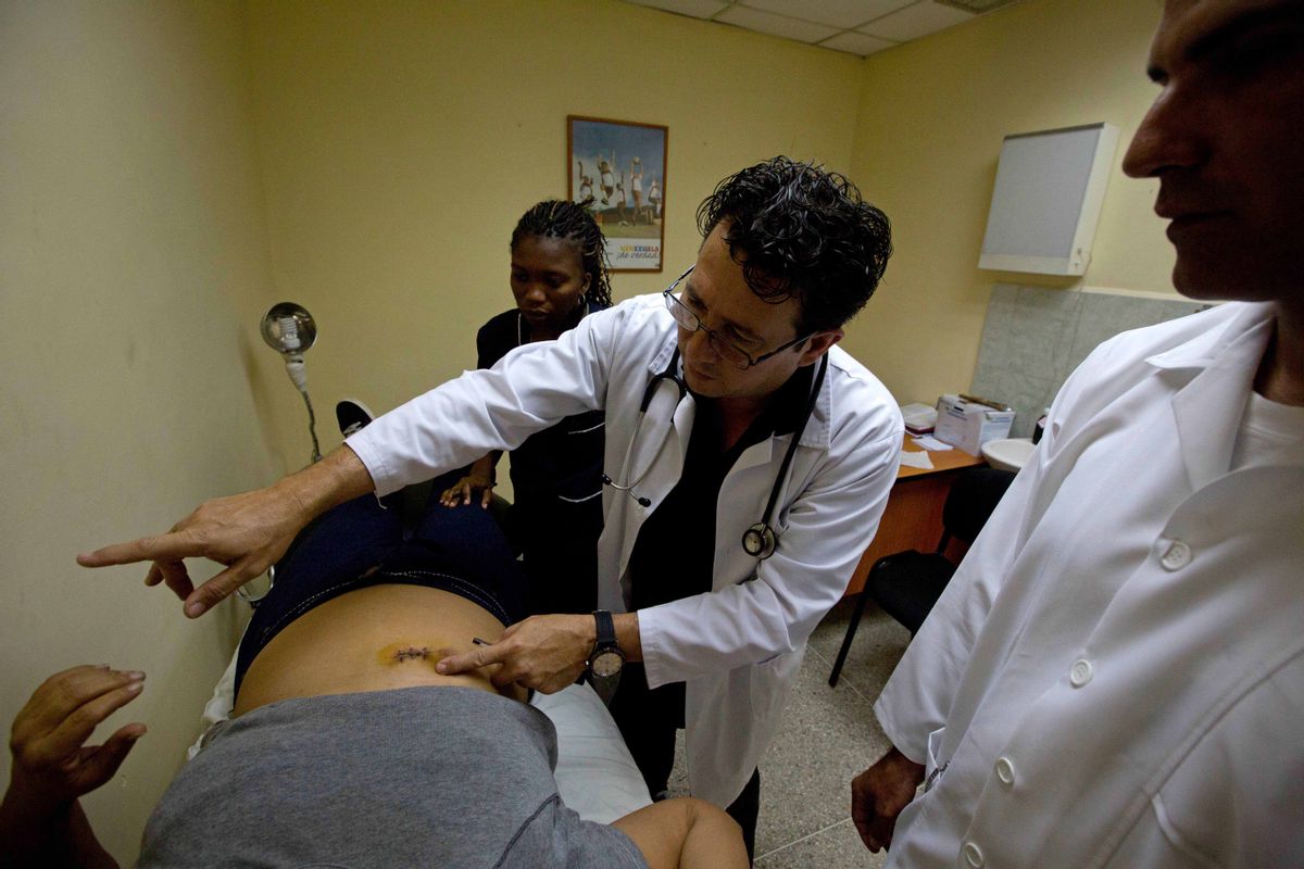 In this March 27, 2014 photo, Omar Fernandez, a Cuban doctor, examines a patient at a medical center in the Petare shanty town of Caracas, Venezuela. Cuban doctors offer free emergency, ophthalmology and pediatric care, as well as minimally invasive surgical procedures. Some also minister to gunshot victims and drug and alcohol addicts. (AP Photo/Fernando Llano) (AP)