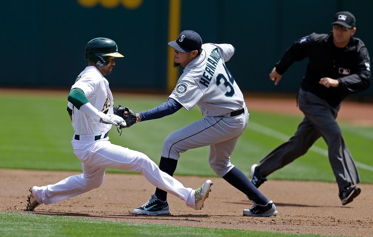 Seattle Mariners pitcher Felix Hernandez, right, tags out Oakland Athletics' Coco Crisp in a rundown between first and second base in the first inning of a baseball game Wednesday, May 7, 2014, in Oakland, Calif.      (AP/Ben Margot)