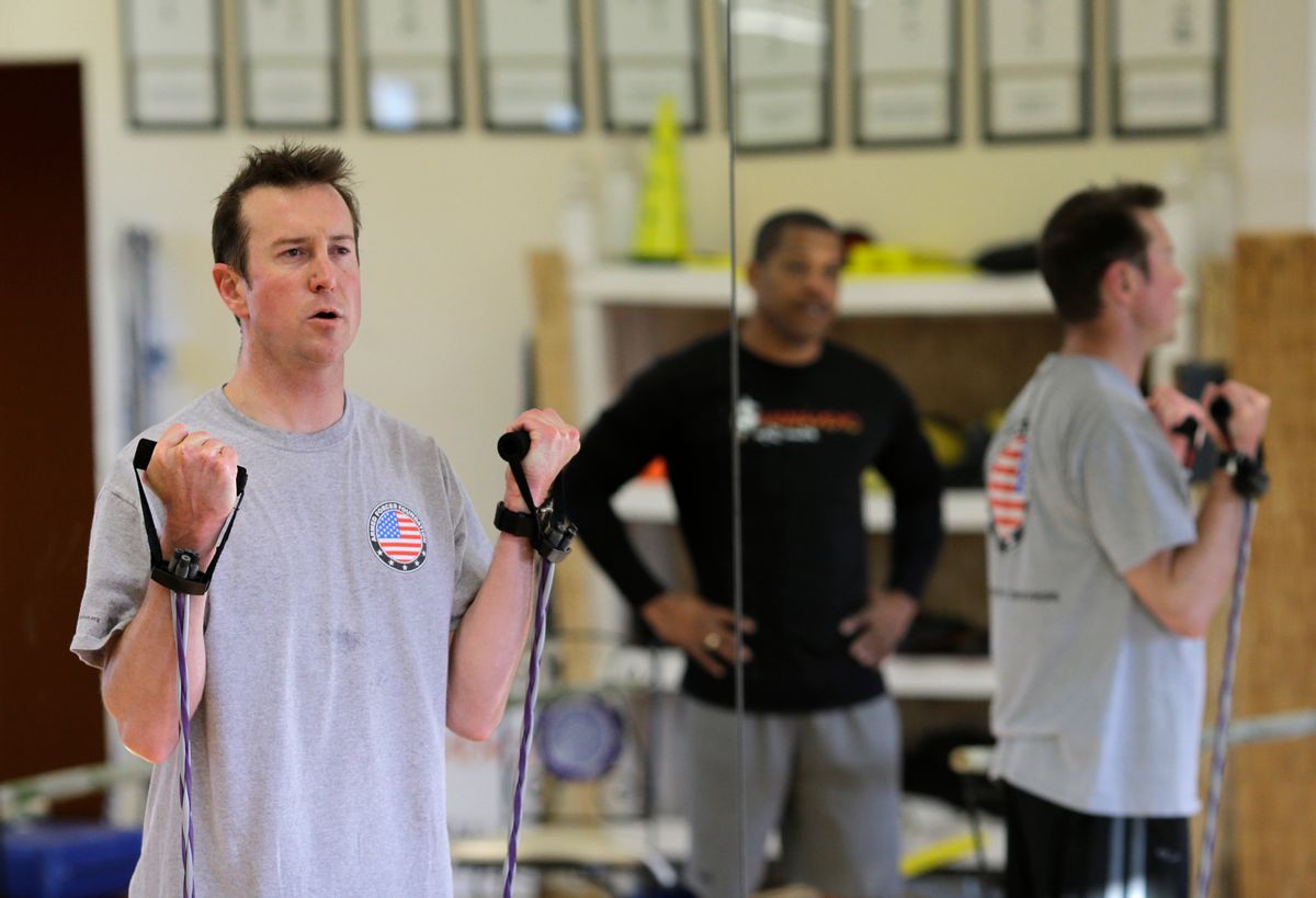 In this photo taken on April 24, 2014, race car driver Kurt Busch works out at a gym in Ellicott City, Md., as trainer Stanley Crump, back right, watches. On Memorial Day weekend, NASCAR's bad boy is trying to own the title of baddest man on the track by pulling off racing's version of an IronMan triathlon. In a single day, he'll try and race in the Indianapolis 500 and the Coca-Cola 600, with a race or two against the clock thrown in. (AP Photo/Patrick Semansky) (AP)