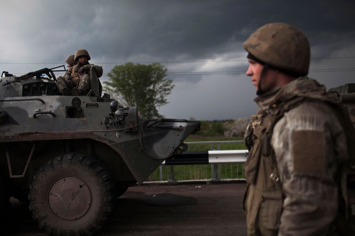 Ukrainian Army soldiers are seen atop an armoured vehicle while Pro Russia civilians block the road in the village of Andreevka, 10 km south of Slavyansk , Ukraine, Friday, May 2, 2014.  Russia has massed tens of thousands of troops in areas near Ukraines border. Kiev officials claim Russia is preparing to invade and that it is fomenting the unrest in the east, where insurgents have seized government buildings in about a dozen cities in towns. Moscow denies the allegations, but Foreign Minister Sergey Lavrov has warned Russia would respond to attacks on Russian citizens or interests in the east.  (AP Photo/Manu Brabo) (AP)