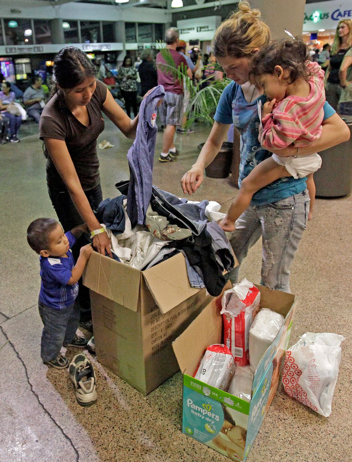 Women and children look through a box of cloths that were donated by volunteers at the Greyhound bus terminal, Thursday, May 29, 2014 in Phoenix.  About 400 mostly Central American women and children caught crossing from Mexico into south Texas were flown to Arizona this weekend after border agents there ran out of space and resources.  Officials then dropped hundreds of them off at Phoenix and Tucson Greyhound stations, overwhelming the stations and humanitarian groups who were trying to help. (AP Photo/Rick Scuteri) (AP)