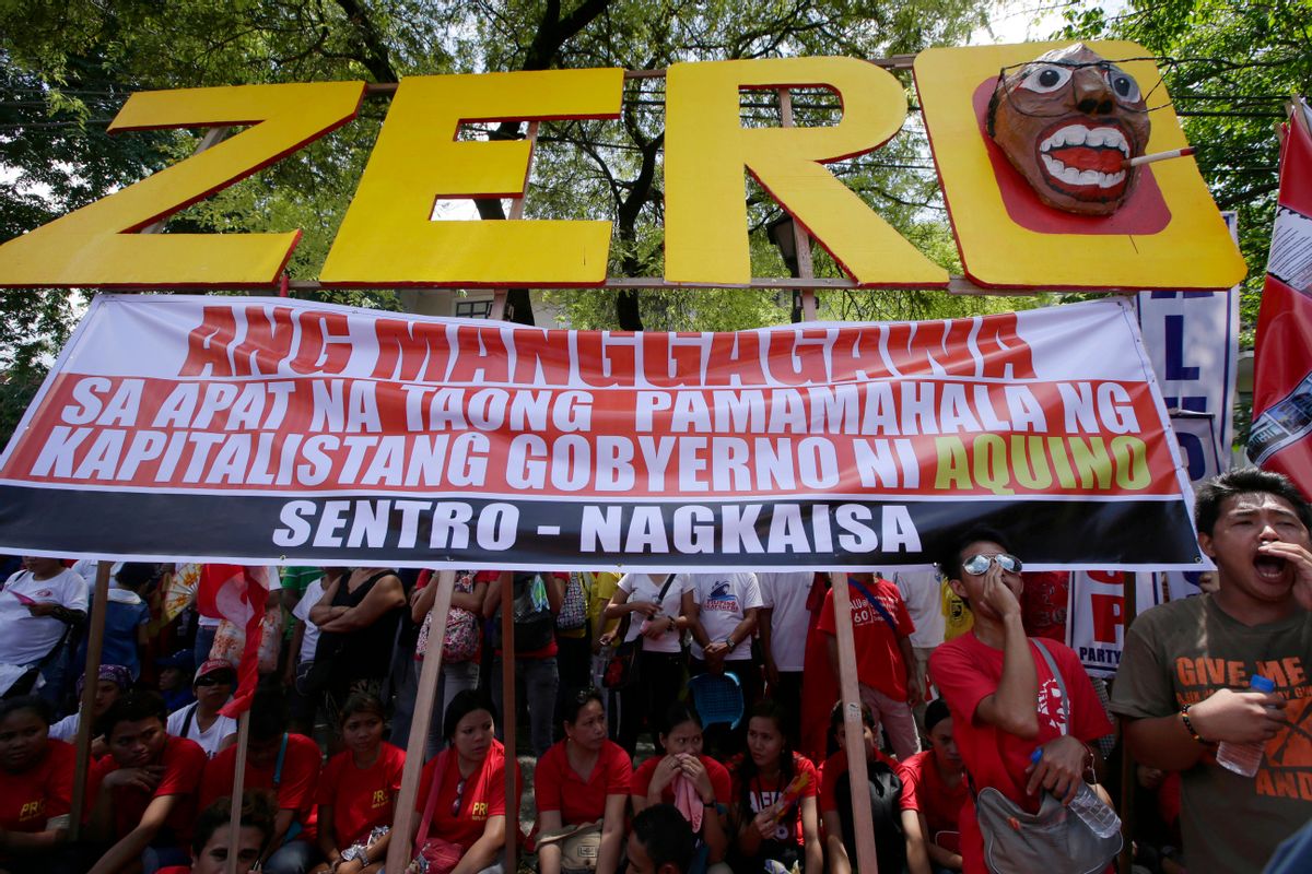 Workers shout slogans as they hold a rally near the Presidential Palace to mark the Labor Day celebrations on Thursday, May 1, 2014 in Manila, Philippines. Various labor groups nationwide held protests, mostly to demand wage hikes, better working conditions and an end to corruption in the government. The sign reads: Workers Have Zero Benefits In The Four Years of Capitalist Government of Aquino. (AP Photo/Bullit Marquez) (Bullit Marquez)