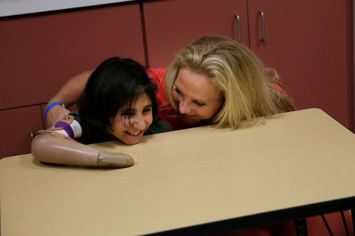 Shah Bibi Tarakhail, a six-year-old Afghan girl whose love of painting won the hearts of U.S. doctors who fitted her with a prosthetic, is tickled by her host mother, Ann Drummond, at Shriners Hospital for Children on Thursday, June 19, 2014, in Los Angeles. Shah Bibi Tarakhail, who lost her right arm and right eye when she picked up a grenade following a firefight between U.S. and Taliban forces in her village near the Pakistan border, returned to the United States on Thursday, after the group that sponsored her first visit said it learned her newfound celebrity made her a subject of death threats at home. (AP Photo/Jae C. Hong) (AP)