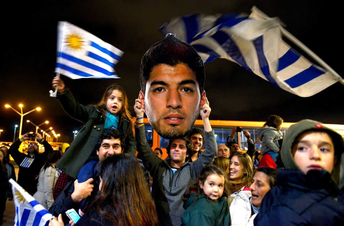Fans of Uruguay's national soccer team await the arrival of Uruguay player Luis Suarez at Carrasco International Airport in the outskirts of Montevideo, Uruguay, Thursday, June 26, 2014. The Uruguay forward, widely regarded as one of the best players in the world, was banned by FIFA from all football for four months on Thursday for biting an Italian opponent in an incident that marred the team's victory and progression to the second round. (AP Photo/Matilde Campodonico) (AP)