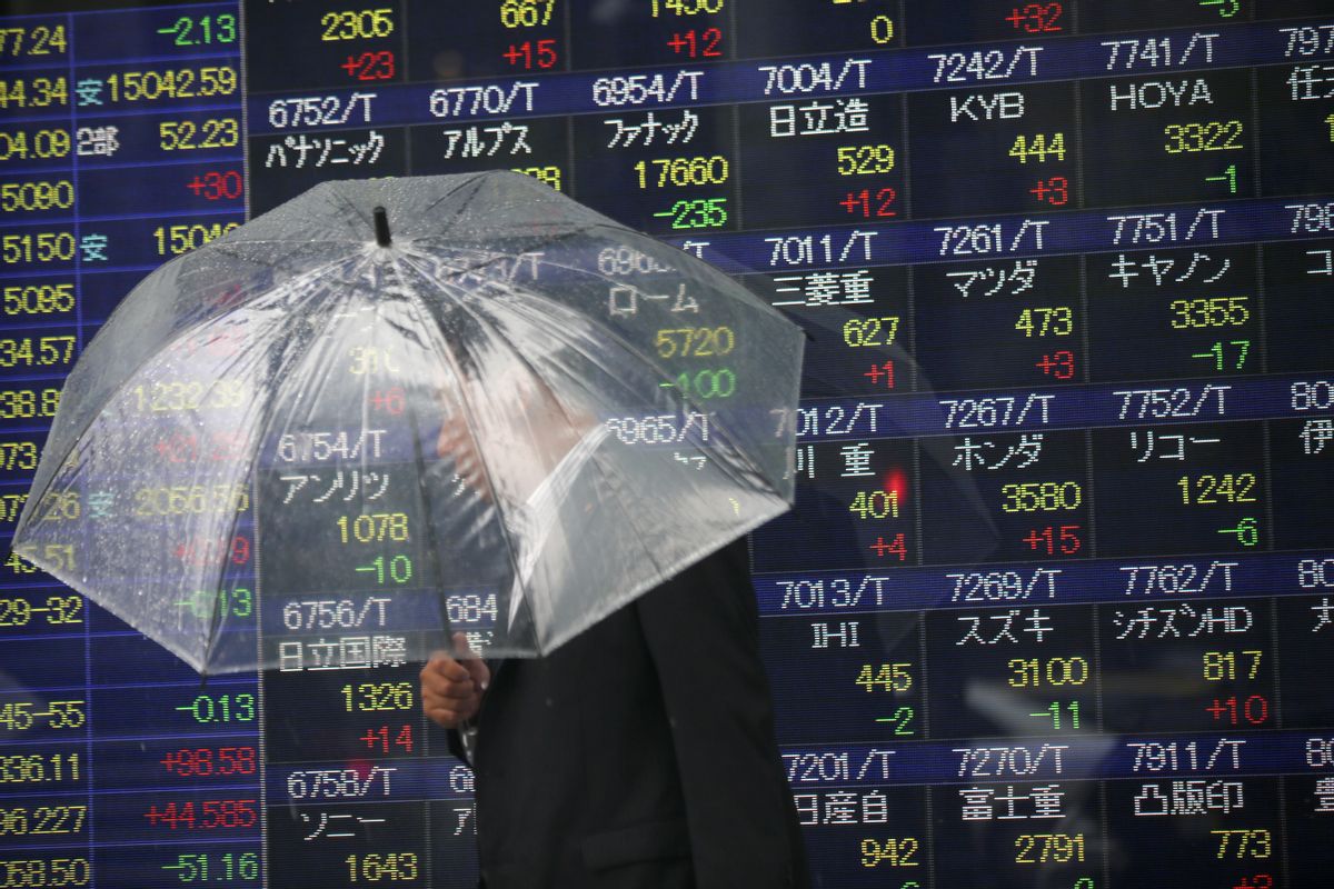 FILE - In this June 6, 2014 file photo, a man holding an umbrella walks past an electronic stock indicator of a securities firm, in Tokyo. The Treasury Department releases foreign holdings data for April on Monday, June 16, 2014. (AP Photo/Eugene Hoshiko, File) (AP)
