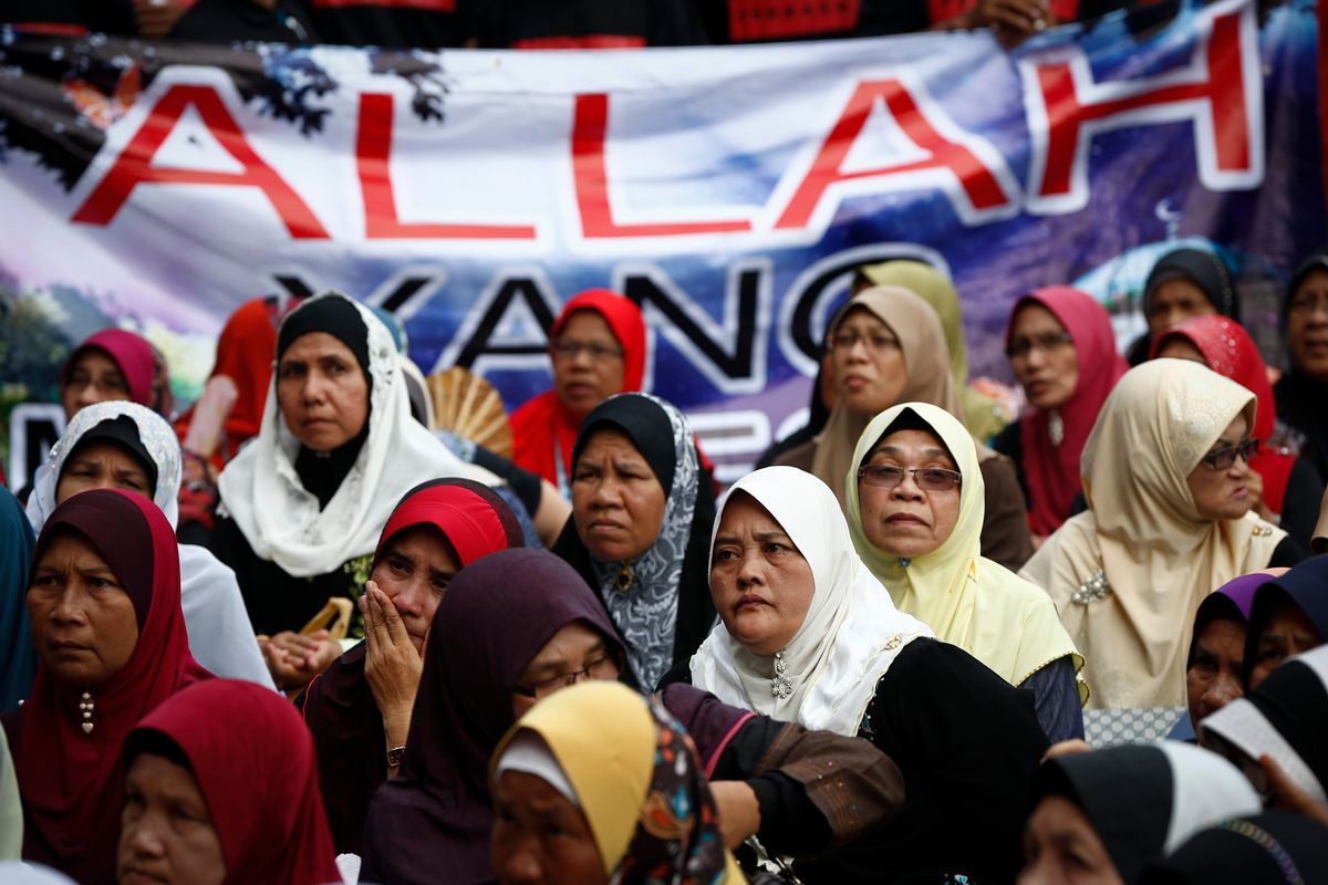 Muslim women sit in front of a banner reading "Allah" during a protest outside the Court of Appeal in Putrajaya, outside Kuala Lumpur, Malaysia, Monday, June 23, 2014. The Federal Court on Monday refused to grant leave to hear the appeal by the Catholic church over the word Allah in its newspaper.   (AP Photo/Vincent Thian) (AP)