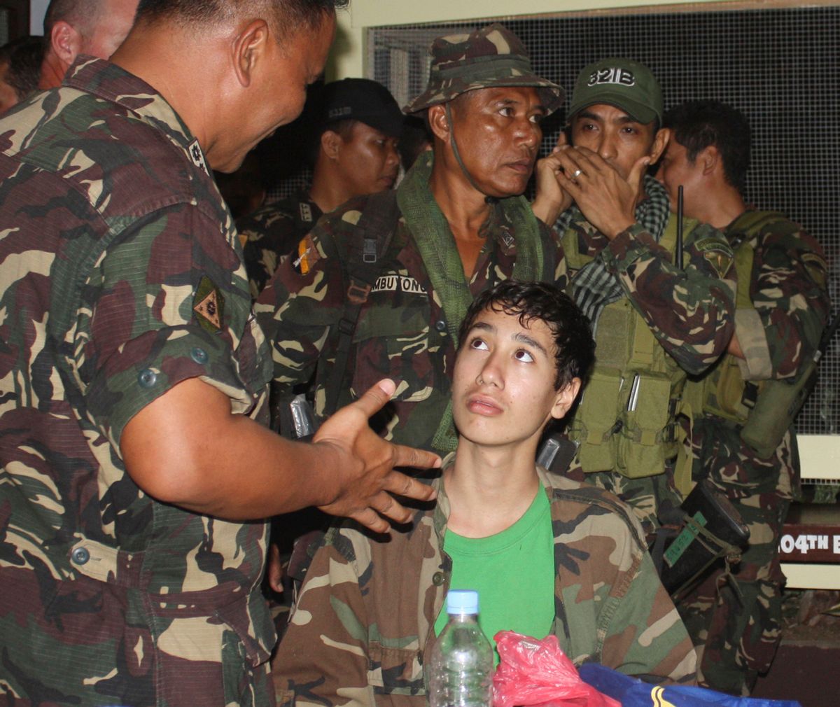In this photo taken Saturday Dec. 10, 2011, Kevin Lunsman, a kidnapped American teenage boy, talks to Filipino soldiers inside the Philippine military compound in Zamboanga city, southern Philippines following his escape from suspected al-Qaida-linked militants. Lunsman, 14, wandered without shoes for two days in a southern Philippine jungle before villagers found him, ending his five-month captivity, officials said Sunday. Lunsmann, claimed to have told his four armed captors that he would take a bath in a stream and then made a dash for freedom Friday in Basilan province, police Senior Supt. Edwin de Ocampo said. He followed a river down a mountain until villagers found him late the next day, de Ocampo said. (AP Photo) (Anonymous)