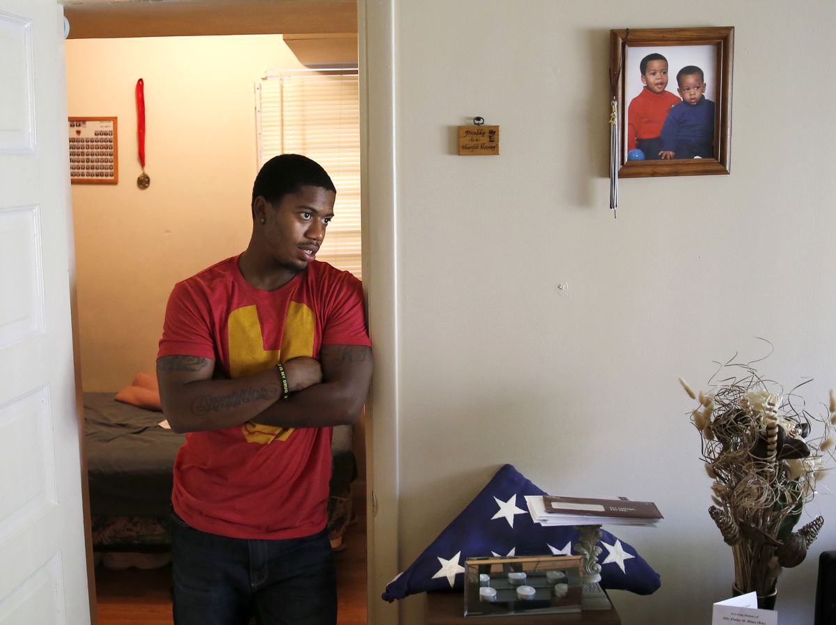 In this May 10, 2014, photo, Rayvaughn Hines stands in the doorway of his bedroom where a photograph of him and his little brother Willie Brown Jr., hangs on the wall and a military funeral flag for his grandmother, Elaine Hines, sits in his mother Shireille's home in Chicago. At 22, Hines, a Gates Millennium scholar and Urban Prep class of 2010 graduate, recently earned his psychology degree from the University of Virginia. (AP Photo/Charles Rex Arbogast) (AP)