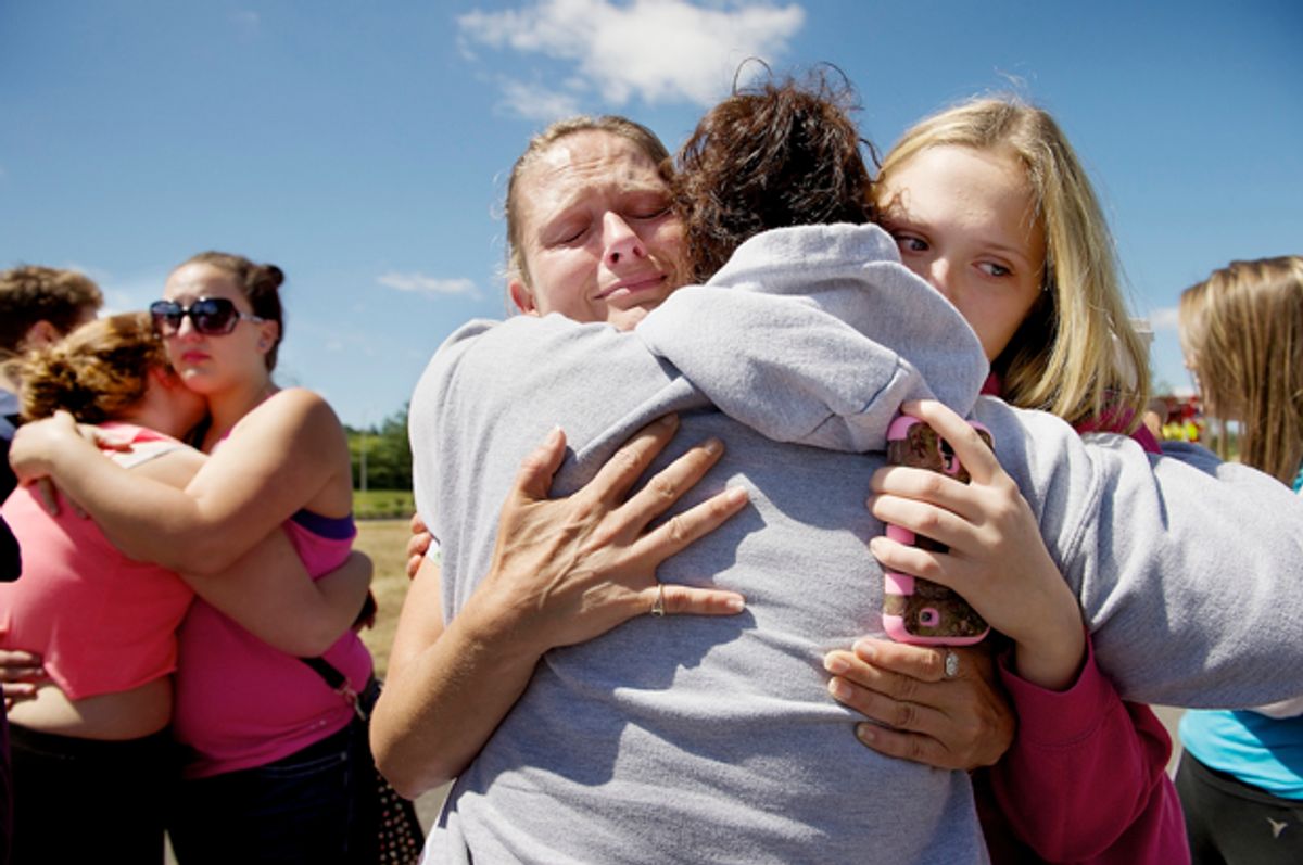 Brandi Wilson, left, and her daughter Trisha, right, embrace Trish Hall, a mother waiting for her student in Wood Village, Ore., after a shooting at Reynolds High School, June 10, 2014, in nearby Troutdale.     (AP/Troy Wayrynen)