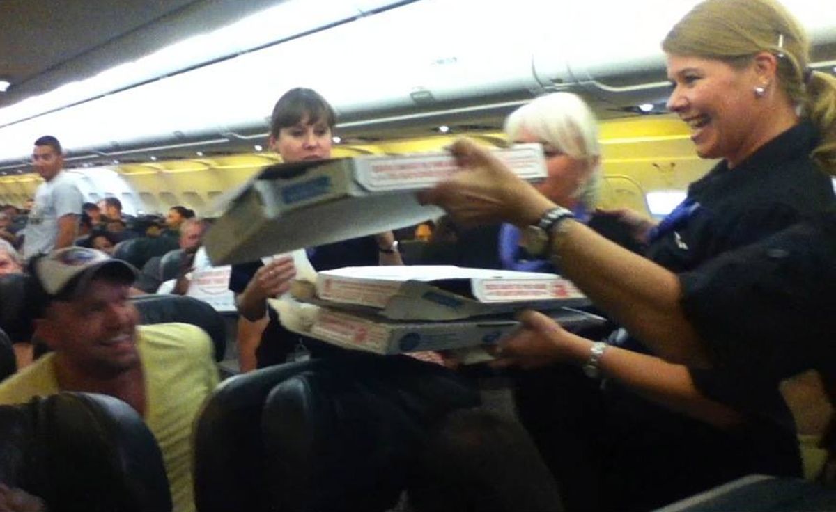 In this photo taken Monday, July 7, 2014, a Frontier Airlines flight attendant passes out pizza to passengers aboard a Denver-bound flight diverted to Cheyenne, Wyo. The airplane pilot treated his passengers to the pizza after they were diverted. (AP Photo/Logan Marie Torres)   (AP)