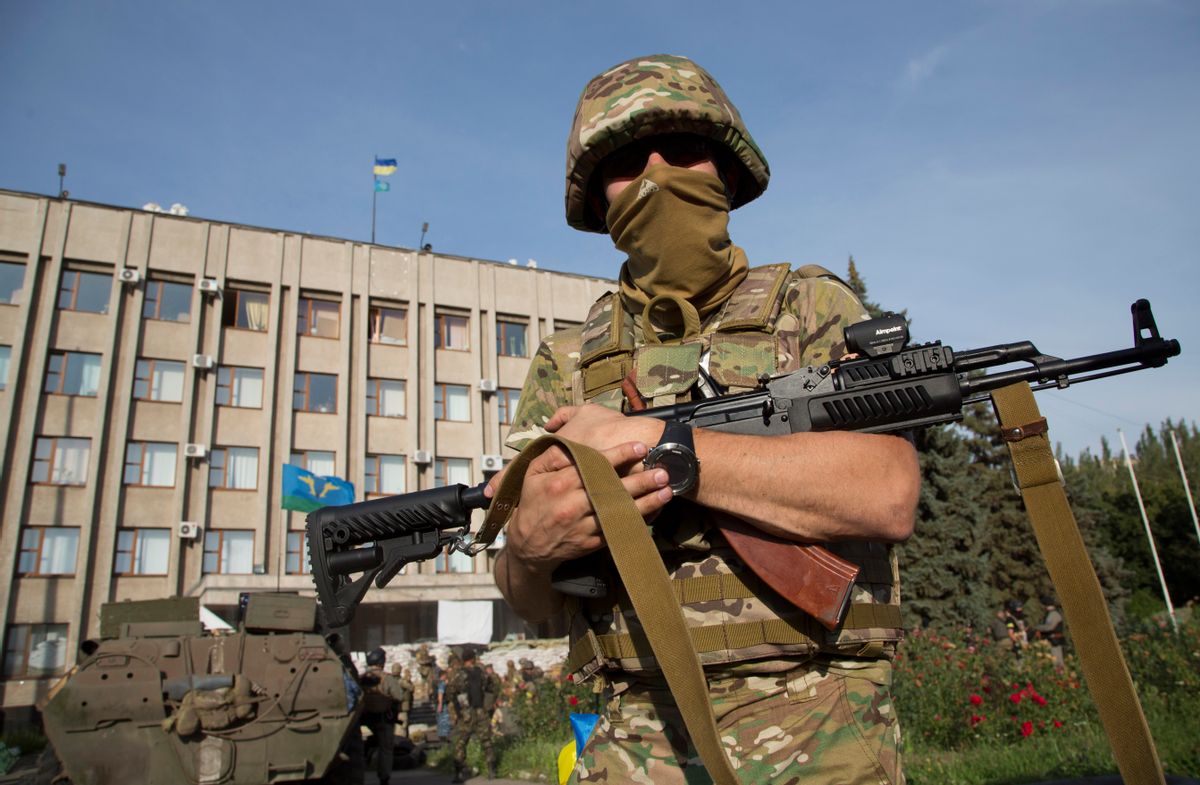 An Ukrainian government army soldier stands in front of the government building with a Ukrainian flag on the roof in the city of Slovyansk. (AP/Dmitry Lovetsky)