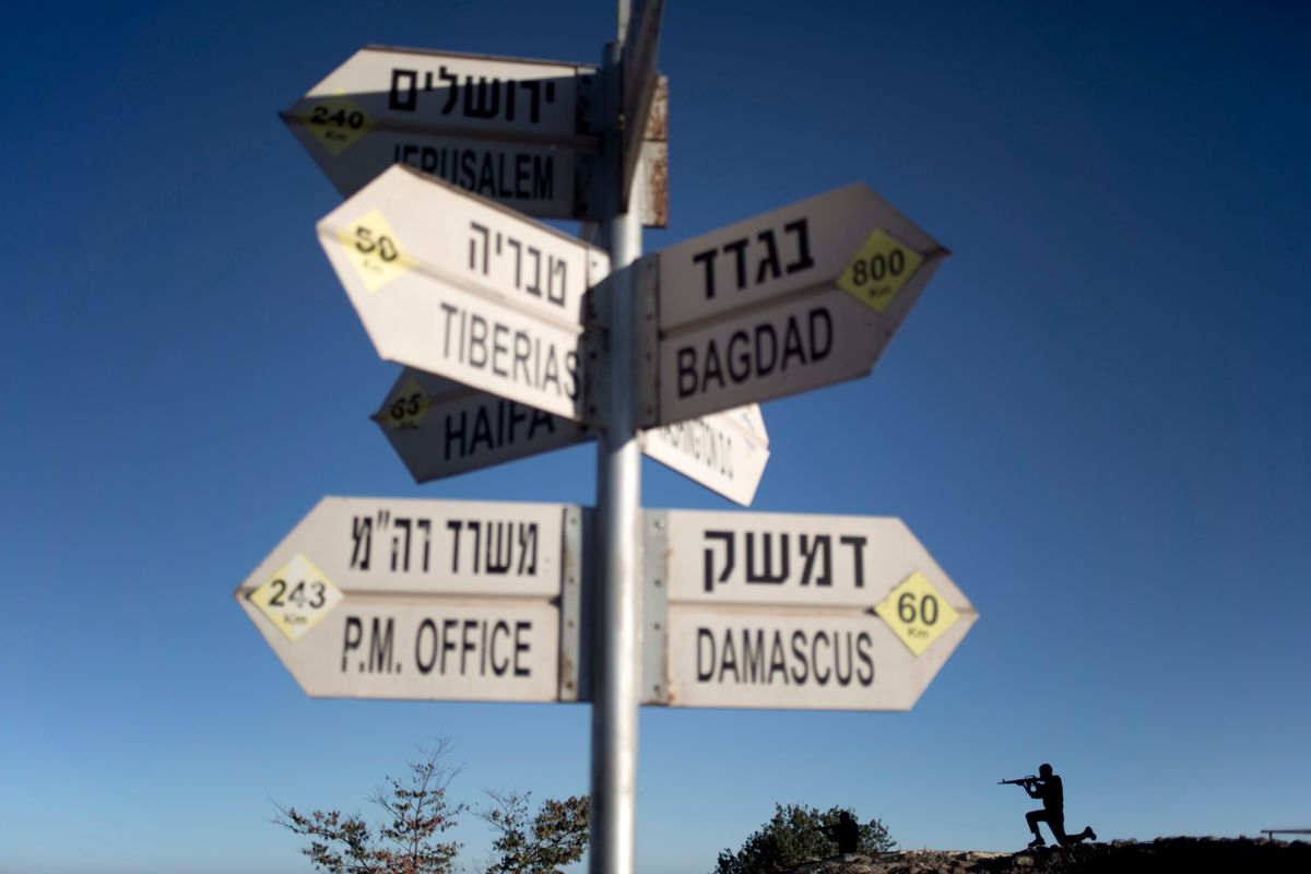 A sign showing the direction and distance to cities stands as a metal board in the shape of a gunman is placed on an old bunker at an observation point on Mt. Bental in the Israeli controlled Golan Heights, overlooking the border with Syria, Thursday, Aug. 28, 2014. (AP Photo/Ariel Schalit) (AP)