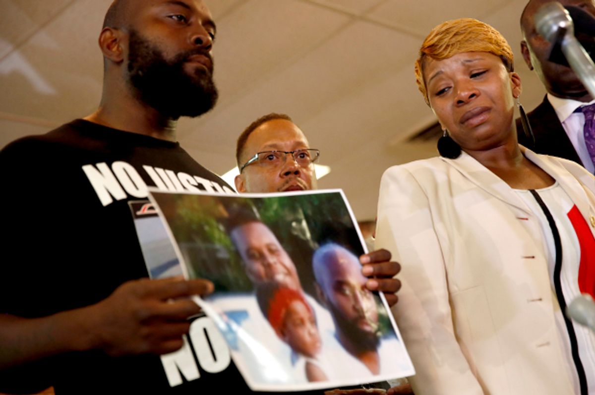 Lesley McSpadden, right, the mother of Michael Brown, watches as Brown's father, Michael Brown Sr., holds up a family picture, Aug. 11, 2014, in Ferguson, Mo.          (AP/Jeff Roberson)