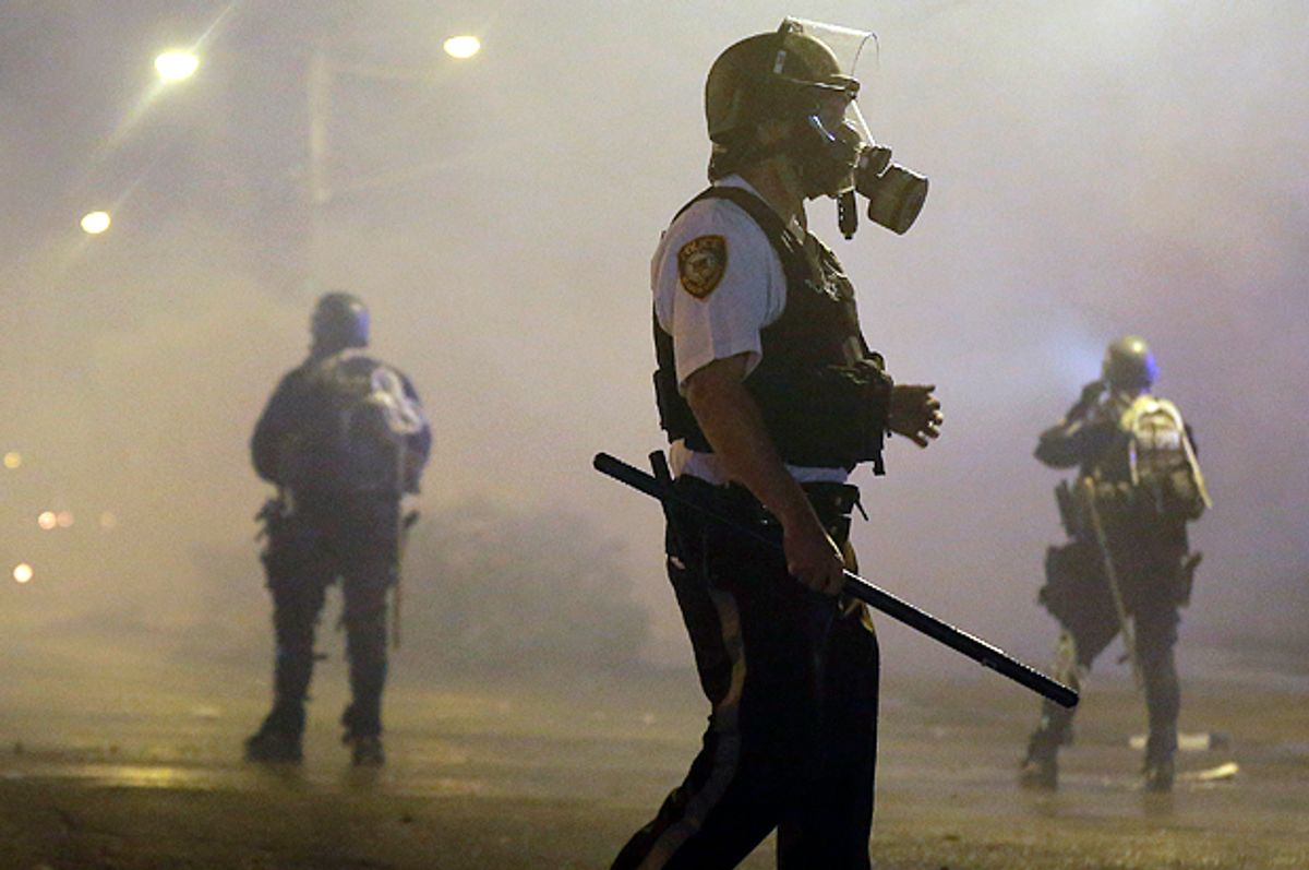 Law enforcement officers wait to advance Sunday, Aug. 17, 2014, after firing tear gas to disperse a crowd in Ferguson, Mo.                     (AP/Charlie Riedel)
