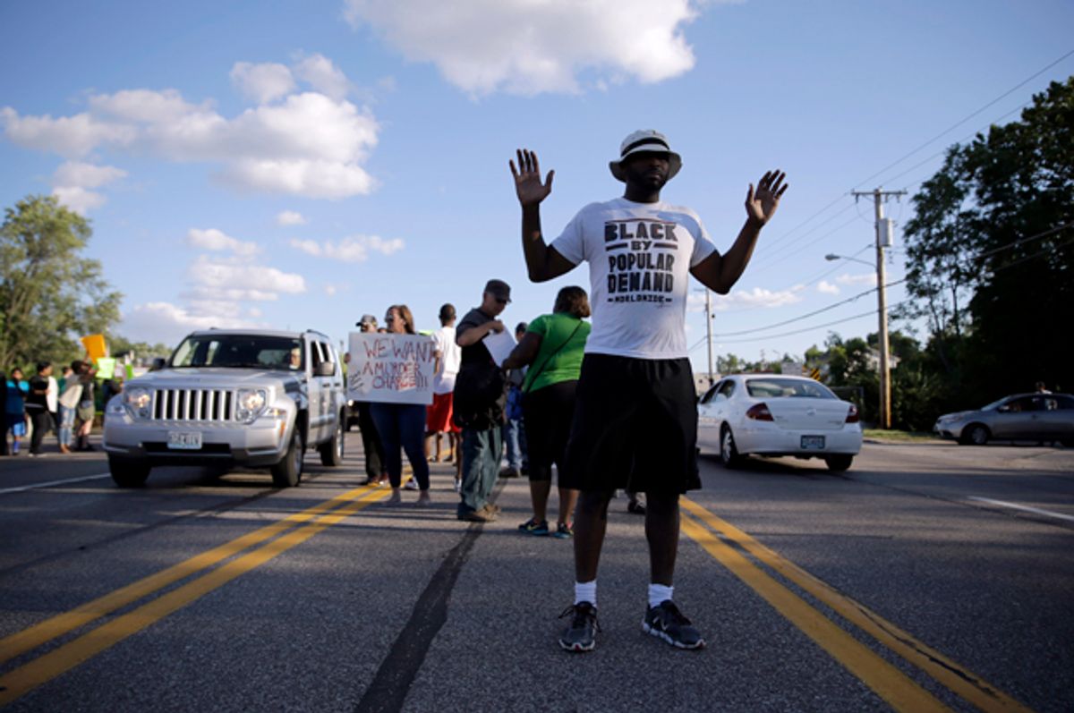 Kenan Morrison stands with his arms raised in the middle of a street, near other protesters, Aug. 12, 2014, in Ferguson, Mo.                        (AP/Jeff Roberson)
