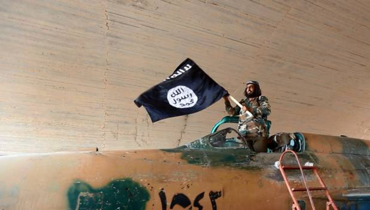 A fighter of the Islamic State group waves ISIS' flag from inside a captured government fighter jet following the battle for the Tabqa air base, in Raqqa, Syria on Sunday  (AP Photo/ Raqqa Media Center of the Islamic State group)