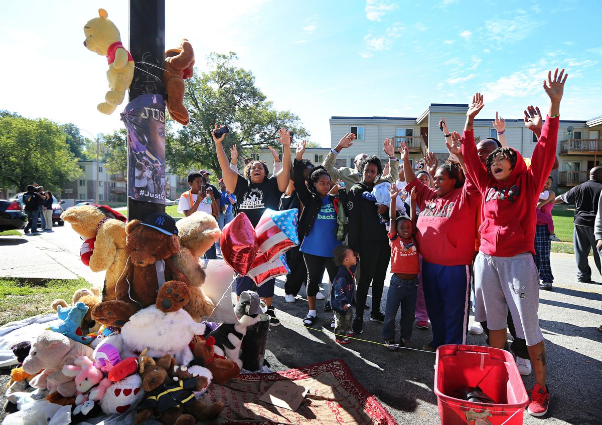 Protesters perform a "hands up, don't shoot" chant at a new teddy bear memorial on Tuesday, Sept. 23, 2014, in Ferguson, Mo., near the spot of where Michael Brown was shot by Ferguson police office Darren Wilson on Aug. 9.  The original teddy bear memorial was destroyed by fire earlier Tuesday morning. Ferguson police spokesman Devin James says the cause of the fire is under investigation.      (AP/St. Louis Post-Dispatch, David Carson)