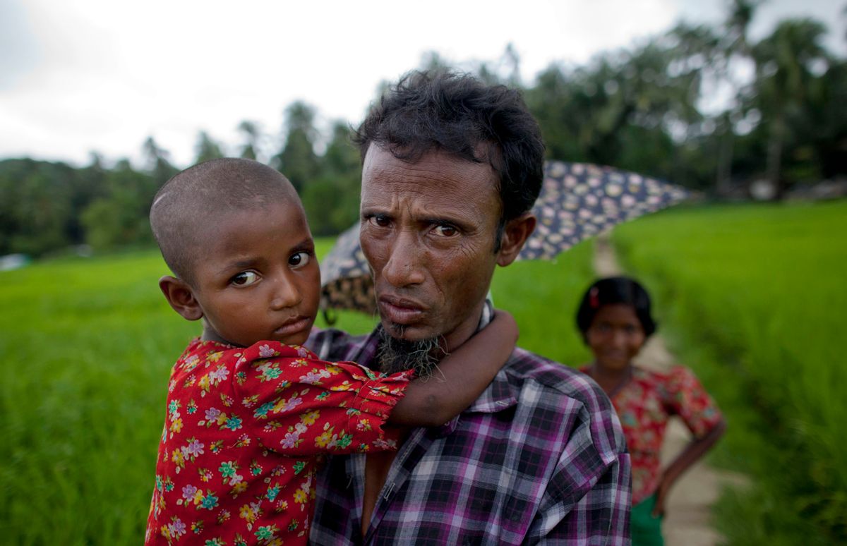 In this Sept. 17, 2013 photo, an ethnic Rohingya man, who was displaced following 2012 sectarian violence, walks carrying his daughter at Nga Chaung refugee Camp in Pauktaw, Rakhine state, Myanmar. Authorities sealed off villages for months in Myanmar's only Muslim-majority region and in some cases beat and arrested people who refused to register with immigration officials, residents and activists say, in what may be the most aggressive effort yet to compel Rohingya to identify themselves as illegal migrants from neighboring Bangladesh. (AP Photo/Gemunu Amarasinghe) (Gemunu Amarasinghe)