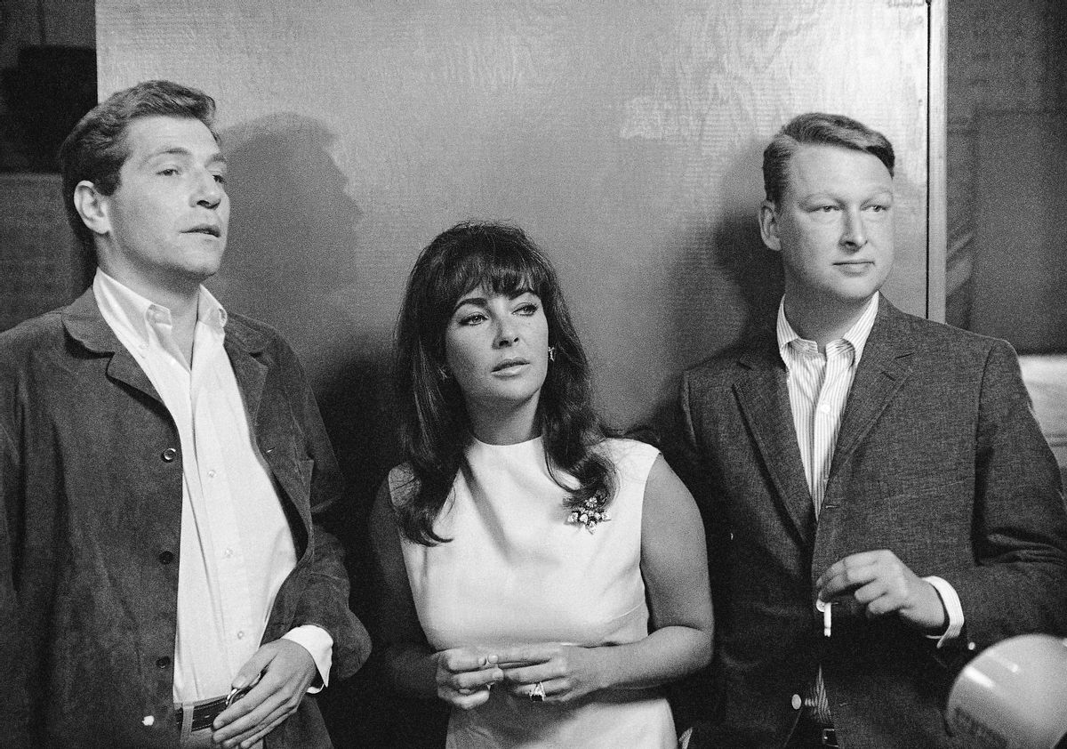 FILE - Elizabeth Taylor is flanked by actor George Segal, left, a co-star in Whos Afraid of Virginia Woolf? and Mike Nichols director of the film, as they watched preparation in this Oct. 20, 1965 file photo taken in Hollywood, ABC News confirms Nichols died Wednesday Nov. 19, 2014. He was 83. (AP Photo/File) (AP)