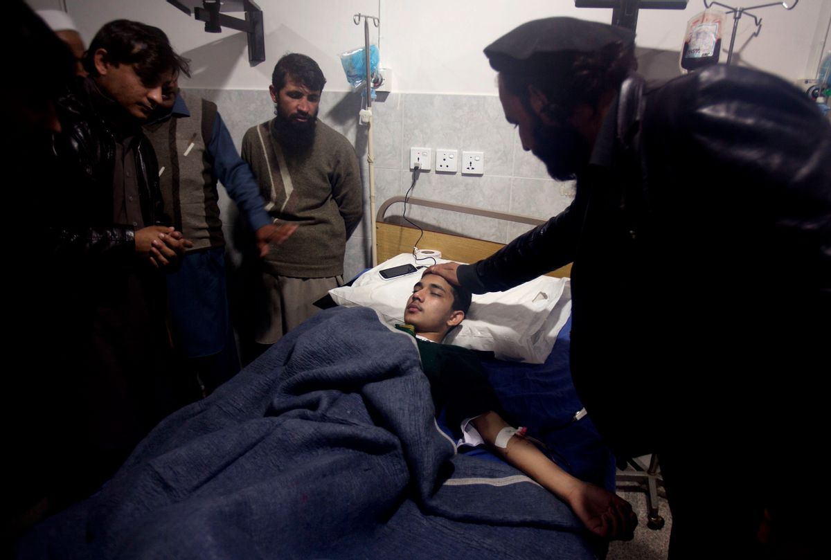 A man comforts a child who survives a Taliban attack on a school that killed more than 100 people, admits at a local hospital in Peshawar, Pakistan, Tuesday, Dec. 16, 2014. Taliban gunmen stormed a military-run school in the northwestern Pakistani city of Peshawar on Tuesday, killing at least 100 people, mostly children, before Pakistani officials declared a military operation to clear the school over. (AP Photo/B.K. Bangash) (AP)