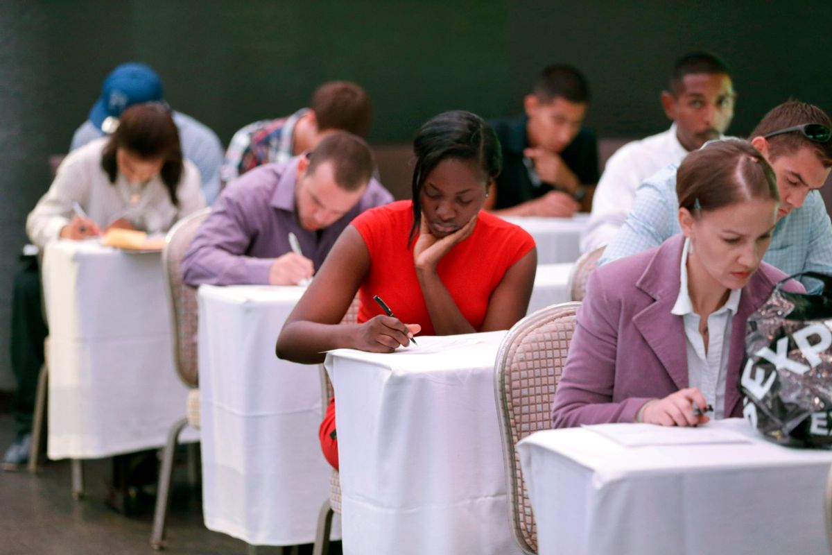 In this Monday, Oct. 6, 2014 photo, job seekers fill out forms before being interviewed during a job fair at Fontainebleau Miami Beach in Miami Beach, Fla. (AP/Wilfredo Lee)