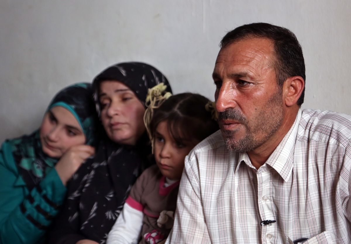 In this Thursday, Nov. 20, 2014 photo, Mohammed Aloun, 43, right, speaks during an interview with The Associated Press as he sits with his family at their house in the northern port city of Tripoli, Lebanon. The Alouns are one of several Syrian families who were given asylum in Uruguay after its government offered to accept 120 refugees. It's a small number compared to the 3 million Syrians who have fled the conflict, now in its fourth year, crowded into overwhelmed neighboring countries or who tried to reach Europe. (AP Photo/Bilal Hussein) (AP)