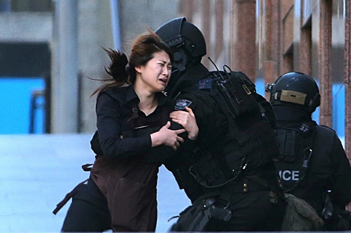 A hostage runs to armed tactical response police officers from a cafe under siege at Martin Place in Sydney, Australia, Dec. 15, 2014.         (AP/Rob Griffith)