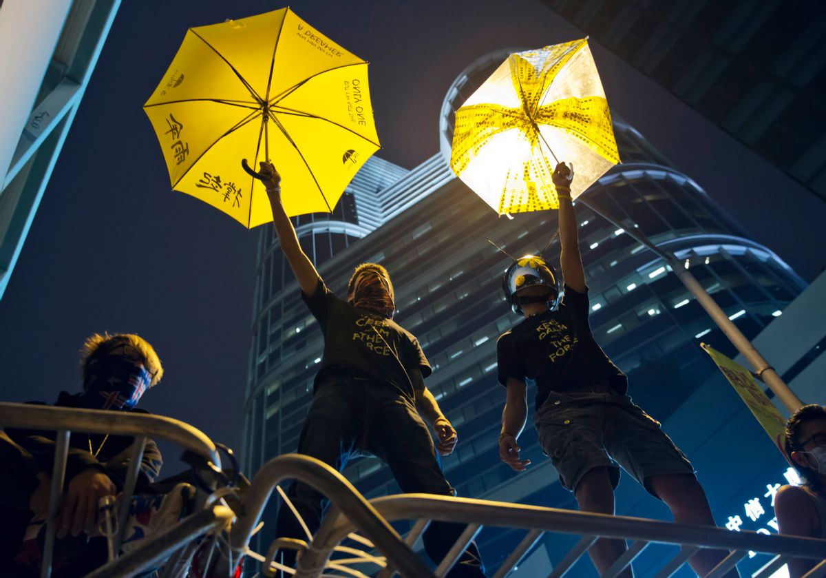 Protesters pose for photographs on a barricade at the occupied area outside government headquarters in Hong Kong Wednesday, Dec. 10, 2014. Hong Kong's dwindling number of pro-democracy protesters vowed Wednesday to stay until the last minute before authorities clear them off a highway where they've been camped out for more than two months. (AP Photo/Kin Cheung) (Kin Cheung)