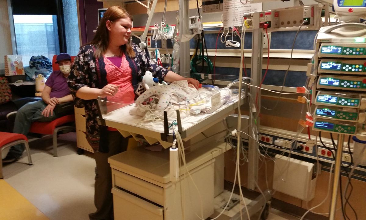 Caylyn Otto stands next to her son, Oliver, at the Phoenix Children's Hospital in Phoenix on Friday, Feb. 13, 2015. Born nearly seven weeks early, the baby is one of the youngest heart transplant recipients at Phoenix Children's Hospital. Doctors say Oliver, who was due Feb. 20, has been doing remarkably well post-transplant. At background left is his father, Chris Crawford. (AP Photo/Terry Tang) (AP)