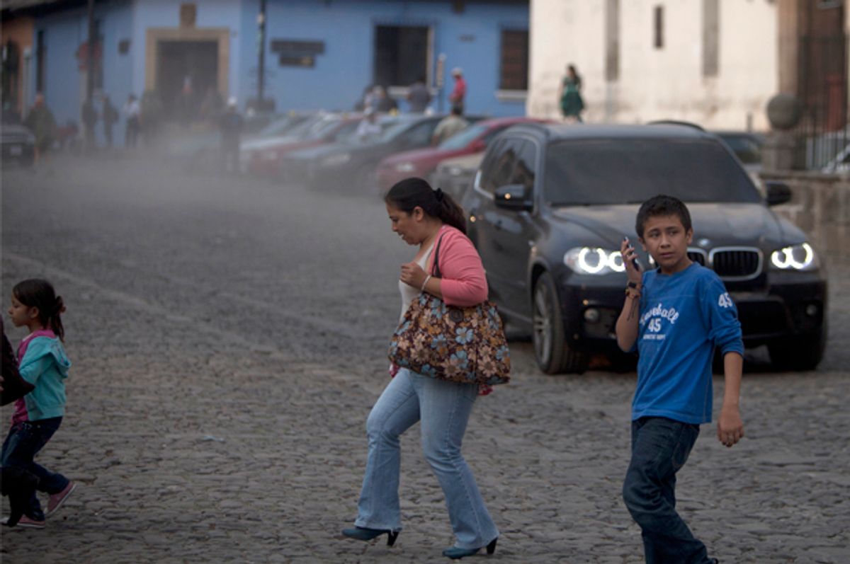People cross a street covered with ash from the eruption of the Fuego Volcano at Antigua Guatemala, Saturday, Feb. 7, 2015.        (AP/Moises Castillo)