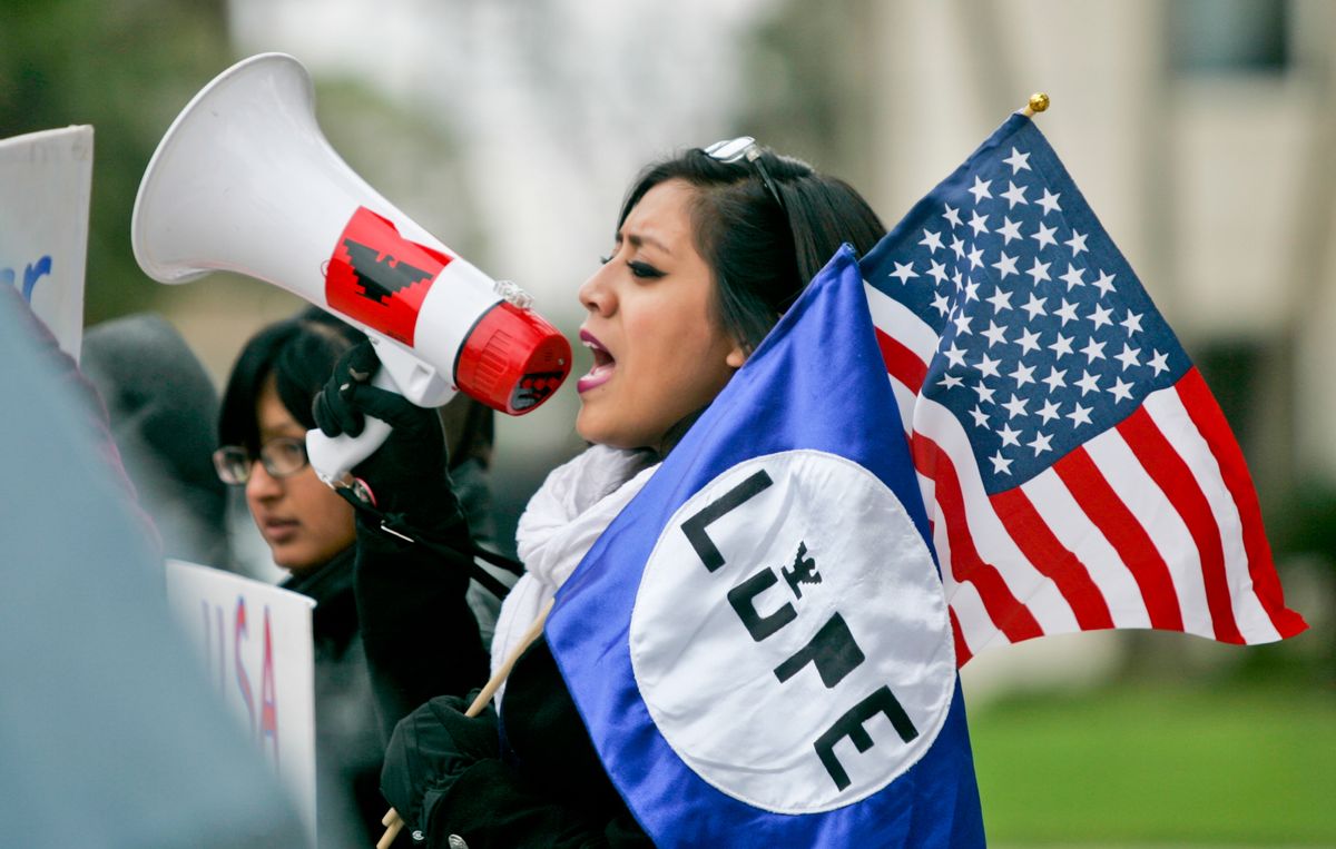 A protester holds an American flag as well as a L.U.P.E flag as she chants in to her megaphone outside of the federal courthouse in Brownsville, Texas, Tuesday, Feb. 17, 2015.  L.U.P.E, La Union del Pueblo Entero is a  non-profit community organizing arm of the farm worker movement. They are protesting the preliminary injunction on immigration case that was granted by U.S. District Judge Andrew Hanen. (AP Photo/The Brownsville Herald, Yvette Vela) (AP)