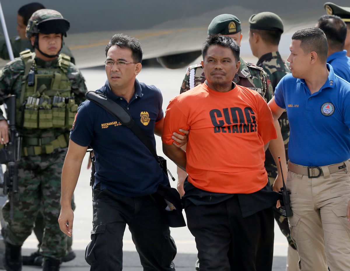 Army and police forces escort handcuffed Mohammad Ali Tambako,  the leader of a Muslim rebel group in the south who has been linked to bombings and a beheading and accused of protecting two terror suspects wanted by the United States, shortly upon arrival at Villamor Air Base at suburban Pasay city south of Manila, Philippines Monday, March 16, 2015. Tambako and five of his men were arrested late Sunday while the militants were traveling in a motorcycle sidecar taxi to a seaport in southern General Santos city.(AP Photo/Bullit Marquez) (AP)