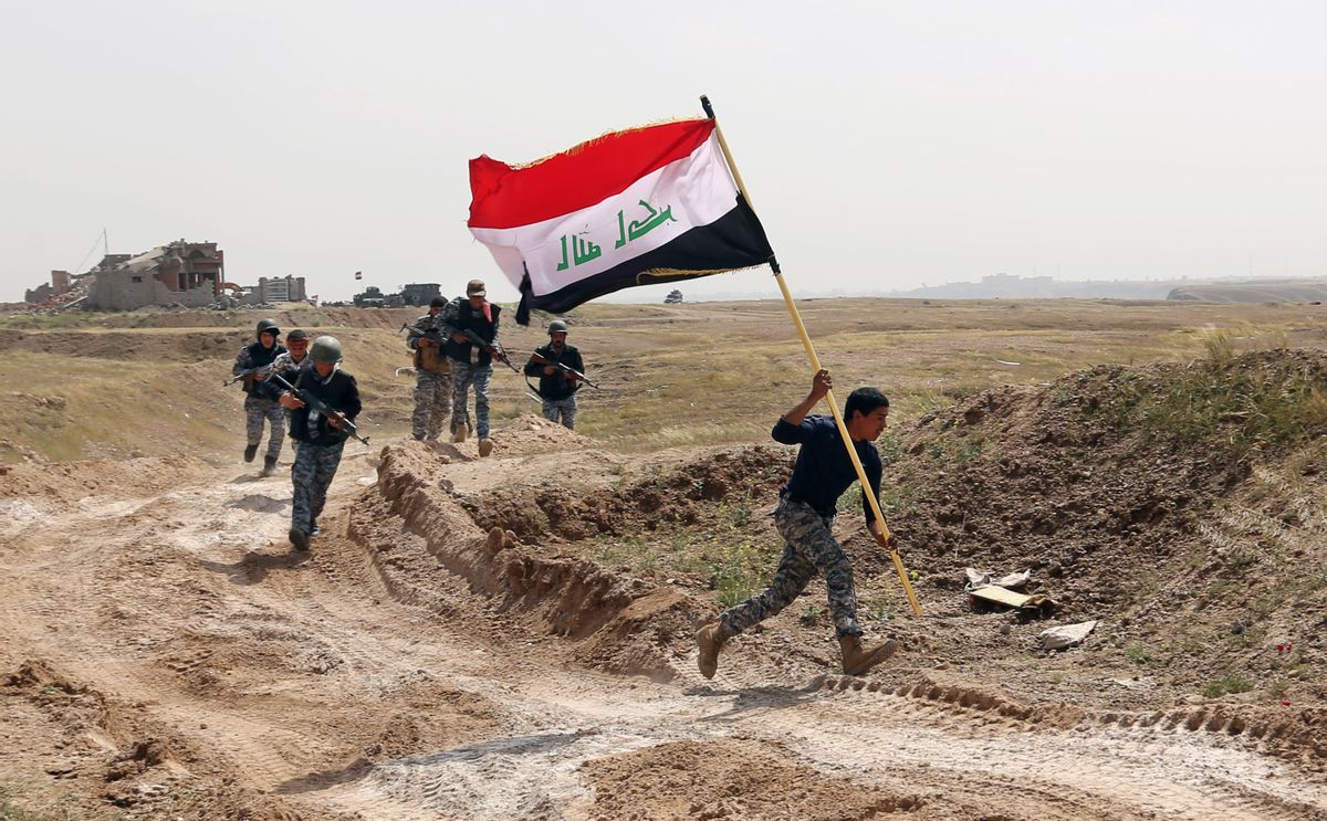 File - This Monday, March 30, 2015 file photo shows a member of the Iraqi security forces running to plant the national flag as they surround Tikrit during clashes to regain the city from Islamic State militants, 80 miles (130 kilometers) north of Baghdad, Iraq. (AP Photo/Khalid Mohammed, File) (AP)