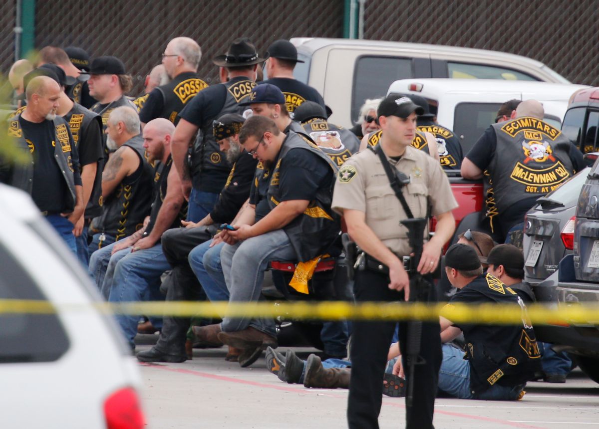 A McLennan County deputy stands guard near a group of bikers in the parking lot of a Twin Peaks restaurant Sunday, May 17, 2015, in Waco, Texas. Waco Police Sgt. W. Patrick Swanton told KWTX-TV there were "multiple victims" after gunfire erupted between rival biker gangs at the restaurant. (Rod Aydelotte/Waco Tribune-Herald via AP)  (AP)
