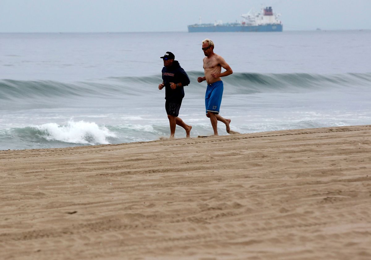Morning joggers make their way along the beach in Manhattan Beach, Calif. on Thursday, May 28, 2015. Popular beaches along nearly 7 miles of Los Angeles-area coastline are off-limits to surfing and swimming after balls of tar washed ashore. The beaches along south Santa Monica Bay appeared virtually free of oil Thursday morning after an overnight cleanup, but officials aren't sure if more tar will show up. (AP Photo/Nick Ut) (AP)