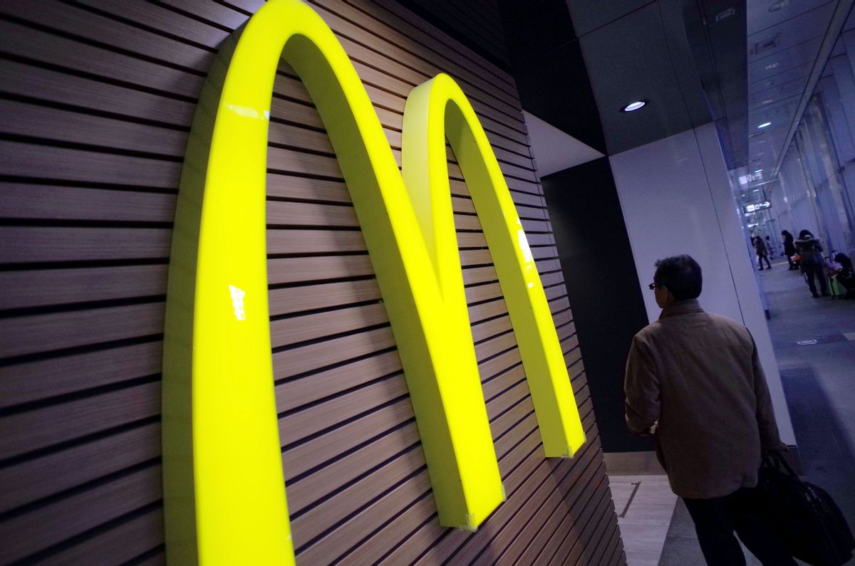 FILE - In this Dec. 17, 2014 file photo, a man walks by a McDonald's logo in front of its restaurant in Tokyo. McDonalds is set to unveil its latest plans to revive its sputtering business on Monday, May 4, 2015. (AP/Eugene Hoshiko)