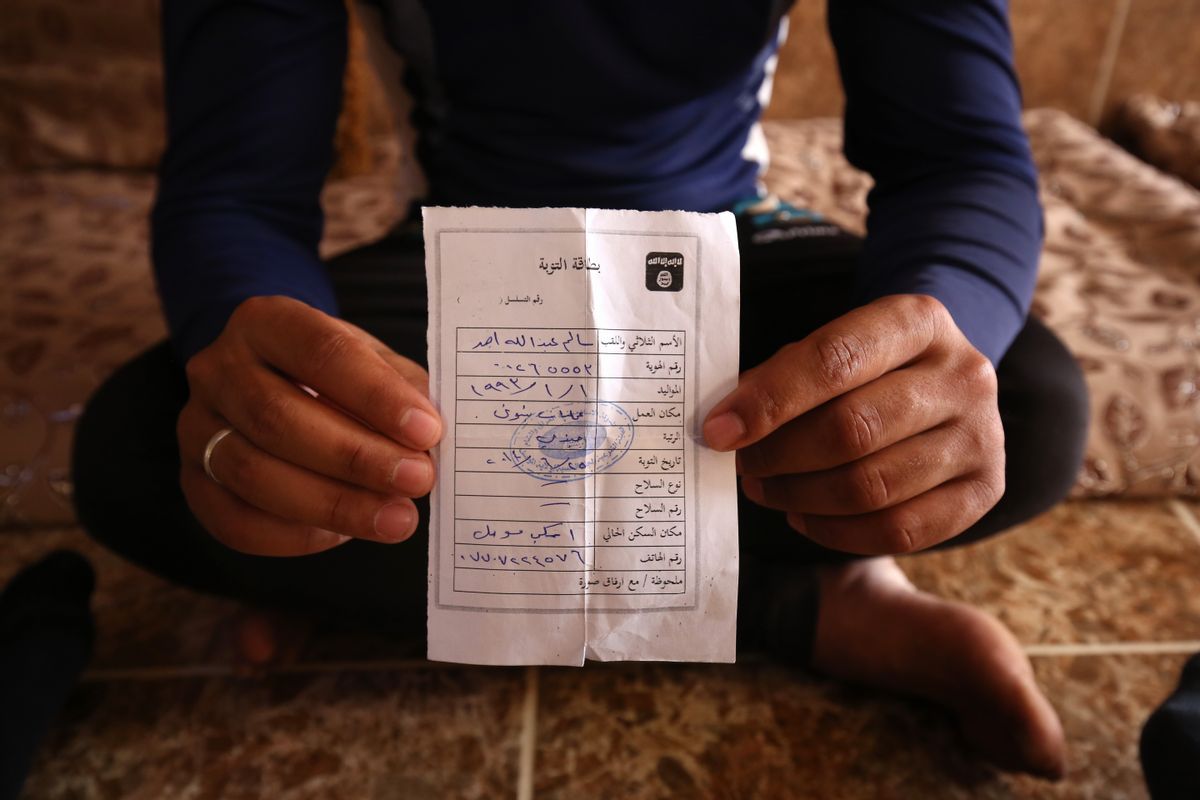 In this Wednesday, May 27, 2015 photo, Salim Ahmed, a former Iraqi Army member, holds the "repentance card" he received from the Islamic State group in June 2014 shortly after the militants took over his home village of Eski Mosul in northern Iraq. The document is part of the apparatus of control the Islamic State group has constructed across its self-declared "caliphate," the territory it conquered in Syria and Iraq. (AP Photo/Bram Janssen) (AP)