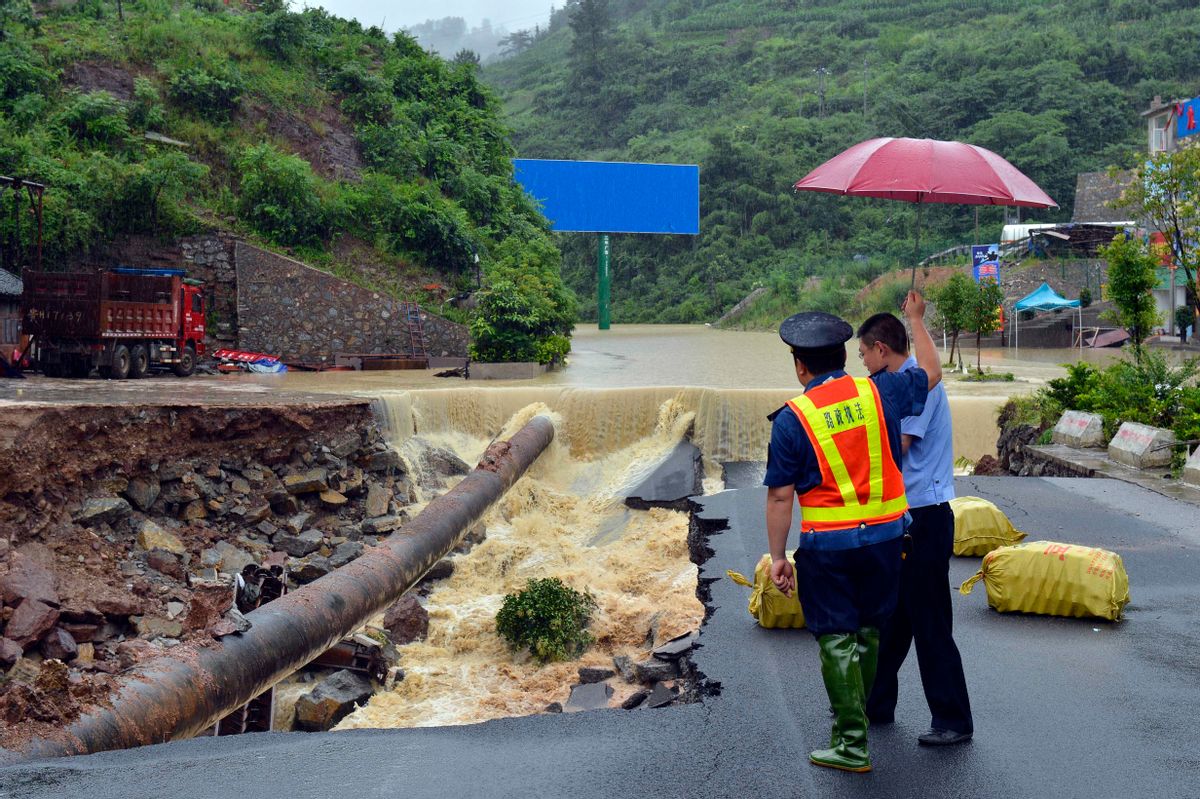 In this Thursday, June 18, 2015 photo, government officials look at a road that collapsed due to flooding in Kaili city in southwestern China's Guizhou province. Heavy storms that swept through several southern Chinese provinces this past week have killed 18 people and left four more missing, according to the Ministry of Civil Affairs. (Chinatopix Via AP) CHINA OUT (AP)