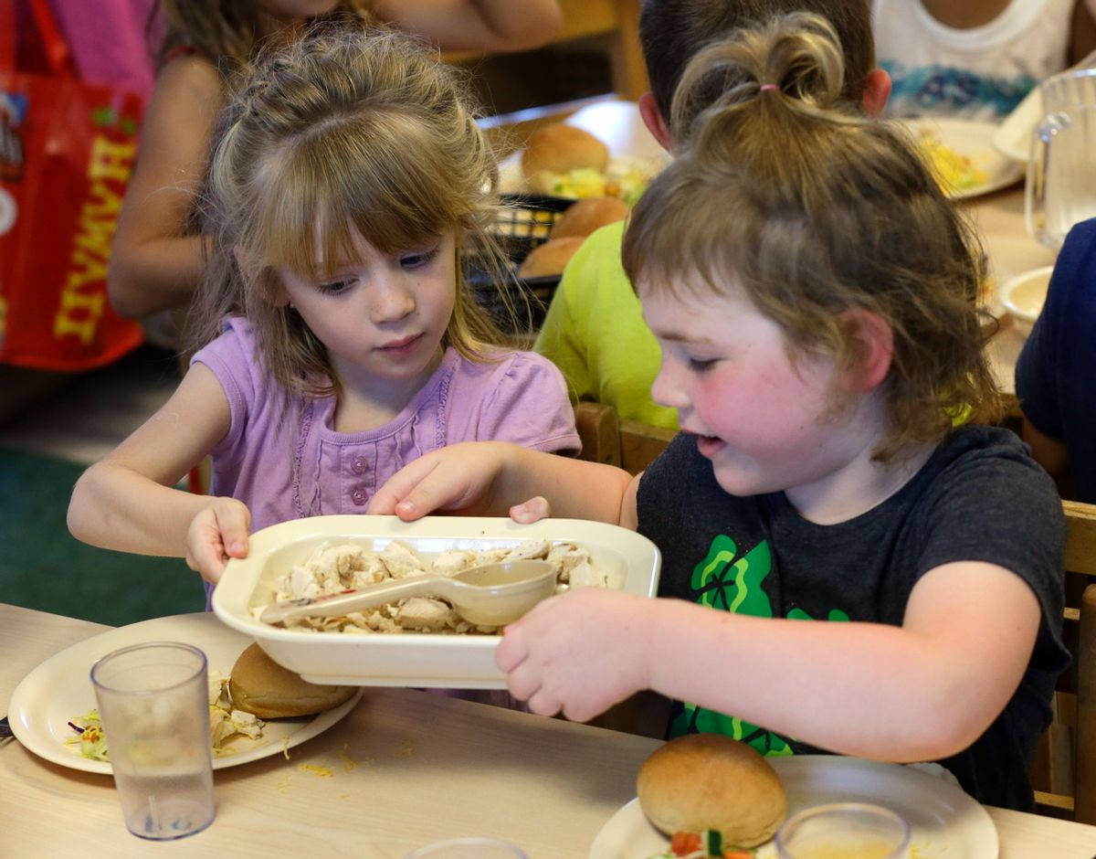 Rebekah Webb, left, shares a family-style meal with Zoe Turner during lunch with other five-year-olds at the Olathe Family YMCA in Olathe, Kan., Wednesday, June 24, 2015. As early childhood teachers lament toddlers too large to fit in playground swings, officials are mulling changes designed to make meals served to millions of kids in day care healthier.  (AP Photo/Orlin Wagner) (AP)