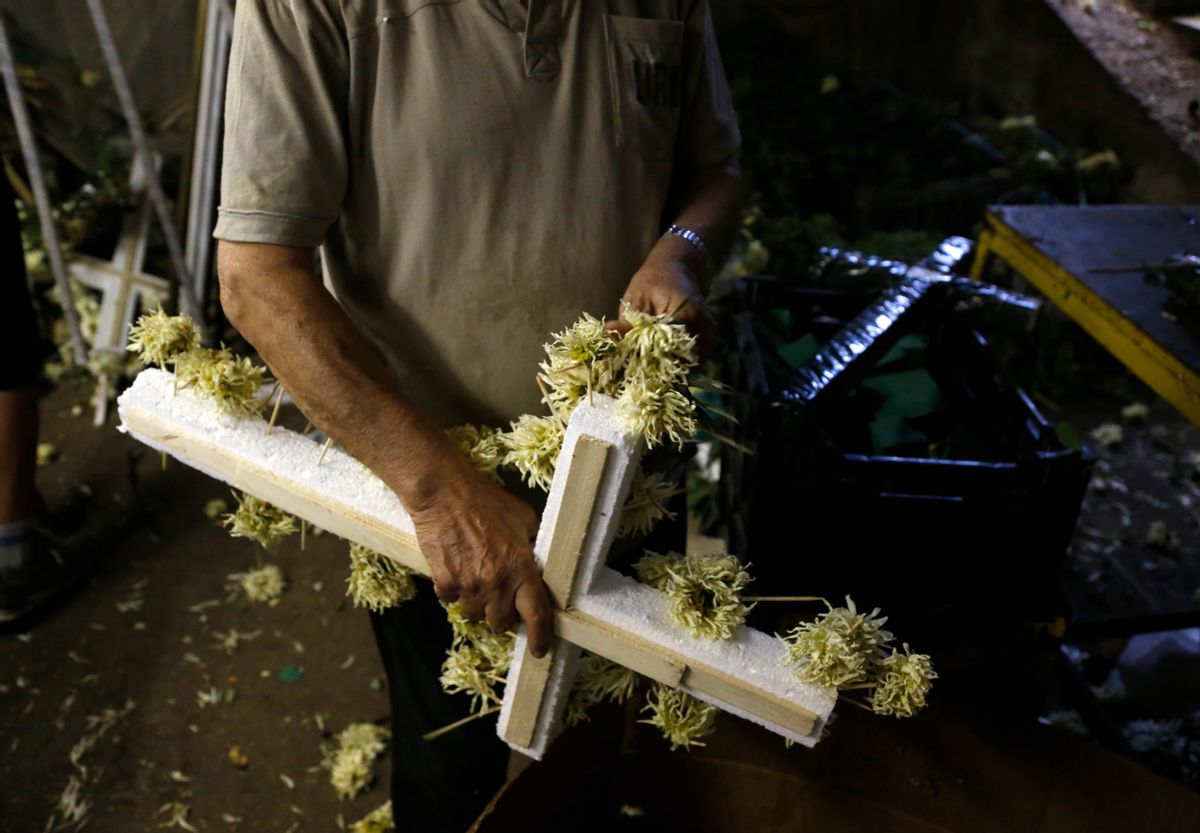A worker removes the flowers from a wreath in Athens, Friday, July 17, 2015. Funeral homes here are struggling to cope with banking restrictions _ with a modest funeral costing more the 15 times the daily ATM withdrawal limit _ in a country that traditionally carries out funerals shortly after death and almost everything is paid for in cash. (AP Photo/Petros Karadjias) (AP)