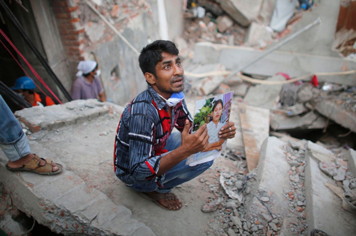A relative holds up a picture of a garment worker in front of the rubble of the collapsed Rana Plaza building, in Savar, April 27, 2013.           (Reuters/Andrew Biraj)
