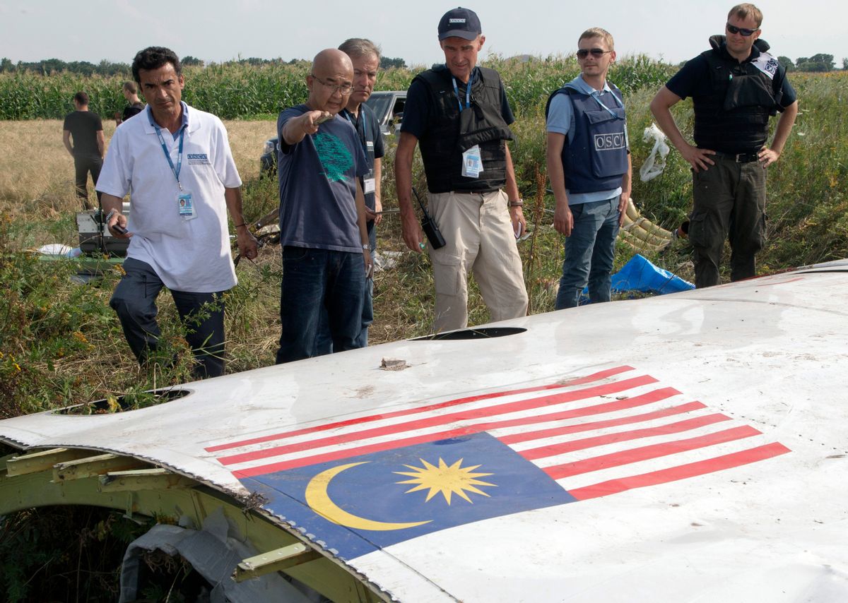 FOR STORY UKRAINE MH17 WHERE THINGS STAND - FILE - In this  Wednesday, July 23, 2014 file photo, Malaysian investigators along with members of the OSCE mission in Ukraine, examine a piece of the crashed Malaysia Airlines Flight 17 in the village of Petropavlivka, Donetsk region, eastern Ukraine. A year since a Malaysia Airlines Boeing 777 was blown out of the sky over war-ravaged eastern Ukraine, killing 298 people, there has been little definitive progress in determining what brought down Flight MH17. (AP Photo/Dmitry Lovetsky, file) (AP)